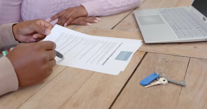 African advisor and client reviewing printed paper at table, advisor pointing pen, client watching