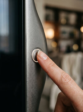 Closeup of a person pressing a power button on a modern silver electronic device