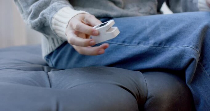 Adult woman noticing clamshell device on tufted seat picking up inspecting testing in sweater jeans