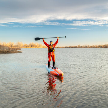 senior male paddler in a drysuit and life jacket is paddling a long racing stand up paddleboard on a lake in Colorado, winter or early spring scenery, recreation, fitness and training concept