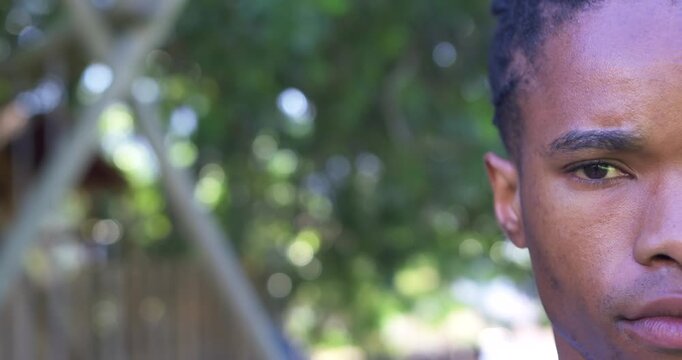 Adult African man facing camera right in backyard by fence, making subtle moves, copy space