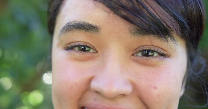 African American woman 20s blinking in garden while camera pulling back revealing lip ring engaging