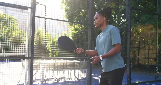 Man adjusting grip, tossing tennis ball, hitting black paddle, training serve on court, copy space