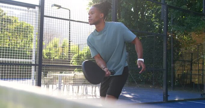 African man reacting to incoming ball stepping into forehand returning on padel court with racket