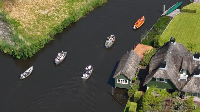 Tourists boating through giethoorn village canals from above
