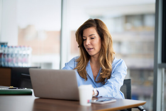 Mature businesswoman using a laptop at a modern office desk