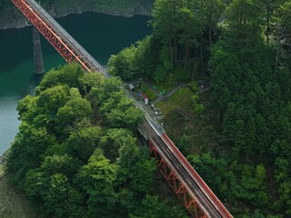 Fototapeta premium Aerial drone photo of Okuoi-Kojou Station and red railway trestle bridge over Lake Setsugyo, Shizuoka, Japan