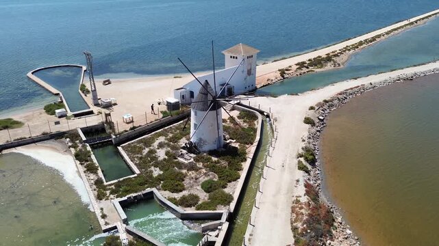 aerial view of Molino la Calcetera historic windmill on salt pans in Mar Menor Murcia Spain featuring white tower structure water channels surrounding landscape and coastal industrial heritage