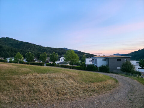germany, spectacular panoramic sunset over elzach village rooftops surrounded by lush schwarzwald nature beneath crystal clear blue summer evening sky