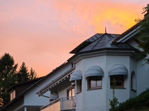elegant modern house facade shining beneath dramatic glowing orange sunset sky showcasing inspiring contemporary architecture in peaceful village