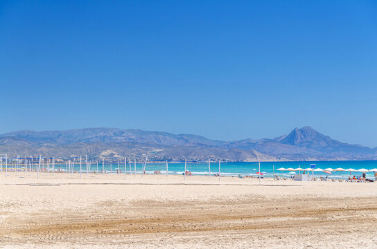 Playa San Juan beach in Alicante city, sports area volleyball courts with volleyball net on sandy beach of Mediterranean Sea coast Costa Blanca in sunny summer day, mountain range background, Spain