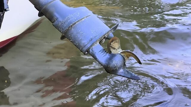 Close-up of an outboard motor propeller submerged in clear lake water while drifting