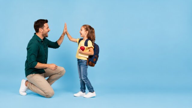 Father and Daughter Celebrating Back to School with High Five on Blue Background