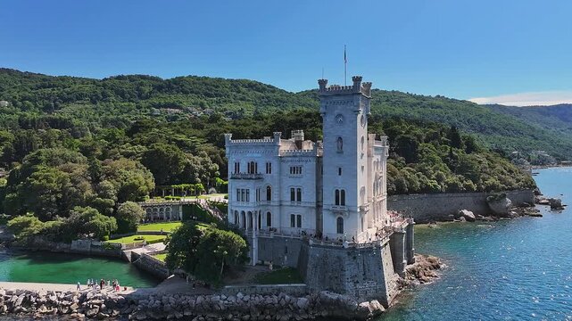 Trieste, Italy - 4K Flying around of the beautiful Miramare Castle (Castello di Miramare) by the Gulf of Trieste on a sunny summer day with blue sky and turqoise sea water