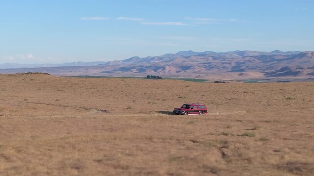 Arid landscape with sparse golden grasses and mountain backdrop