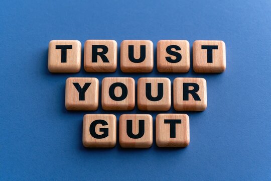 Trust your gut written on wooden letter tiles over a dark blue background