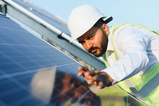 Indian engineer inspecting solar panels for green energy