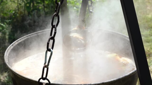 Cooking a large pot of Ukrainian borscht outdoors on a sunny day