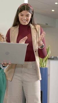 Vertical video: Reacting to coworker with laptop woman in maroon checking report in office by plant