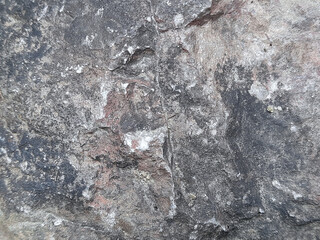 Fototapeta premium Rugged natural stone surface texture with gray black and reddish mineral detail
