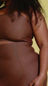 Vertical video: Fixing model curl, posing and laughing as camera rising in yellow set, brown top