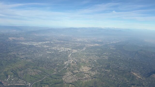 Aerial view of Los Angeles during landing, seen through an airplane window. Expansive cityscape, urban grid and clear skies capture the excitement of arriving in Southern California.