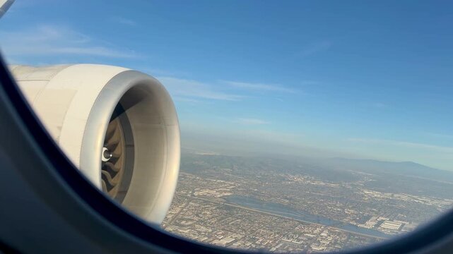 Aerial view of Los Angeles during landing, seen through an airplane window. Expansive cityscape, urban grid and clear skies capture the excitement of arriving in Southern California.