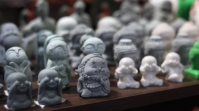Cute Buddha and little monk figurines displayed at Vietnamese souvenir shop in Nha Trang, Vietnam. Small stone and ceramic Asian statues on shelf of local gift market. Tourism and travel concept.