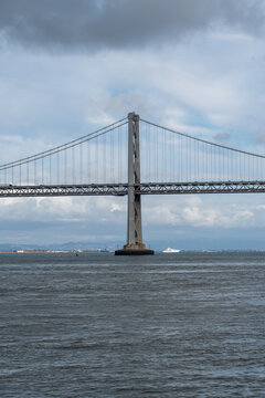 Bridge pier of the San Francisco&ndash;Oakland Bay Bridge beneath a softly clouded sky with subtle blue tones. A striking architectural landmark on the San Francisco waterfront.