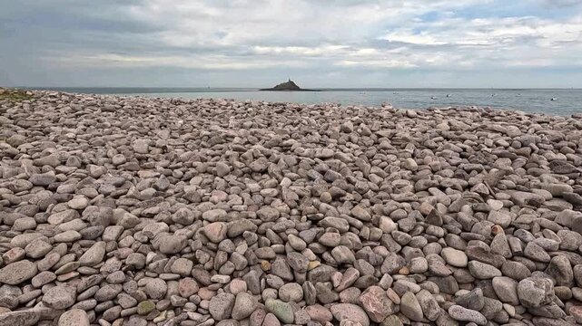 Stone Barriers Along the Beach Help Protect the Coast from Erosion. Slow camera begins on large coastal rocks and smoothly ascends to reveal the vast blue ocean stretching to the horizon.