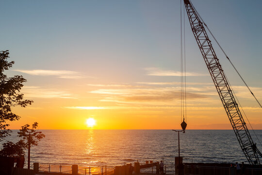 Sunset over the Baltic Sea with construction crane silhouette in Svetlogorsk