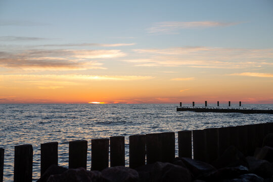 Sunset over the Baltic Sea with wooden pier and rocky shoreline in Svetlogorsk