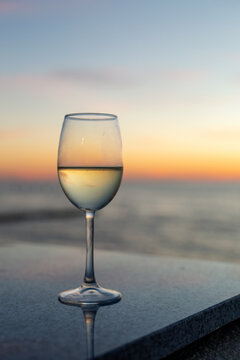 Glass of white wine on a table overlooking the Baltic Sea at sunset
