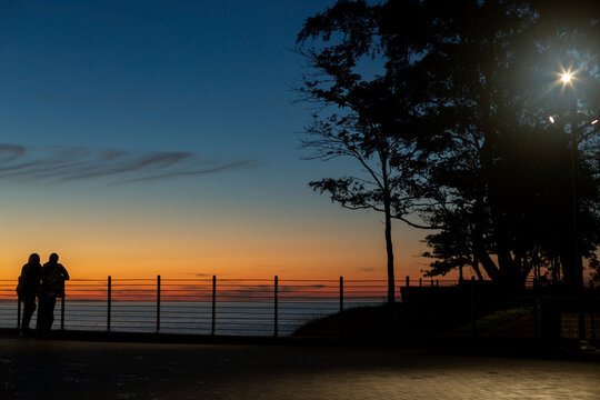 Silhouetted couple standing by Baltic Sea at sunset in Svetlogorsk