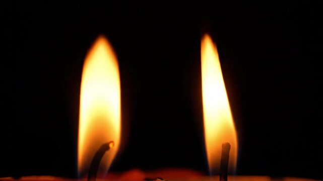 Two candle flames burning in the dark