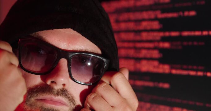 Hooded Hacker Wearing Sunglasses In Front Of Code