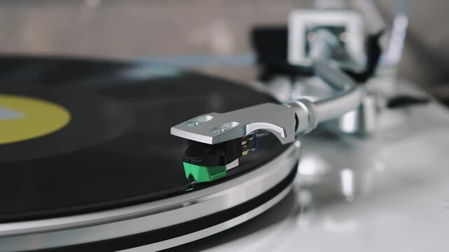Tonearm lowering stylus onto vinyl record on turntable, analog music playback, LP record, HiFi audio, macro close up
