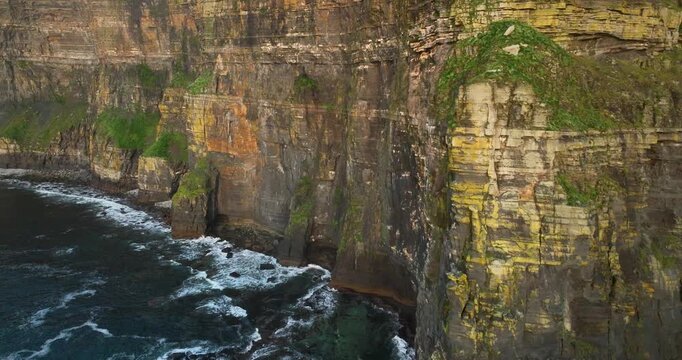 Cinematic aerial drone ascent along towering Cliffs of Moher above Atlantic Ocean, Ireland
