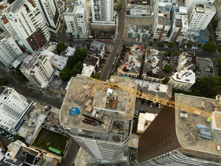 High-angle vertical drone view of a construction crane on top of a modern skyscraper building © hcarbuccia