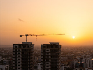 Tower crane on top of residential high-rise buildings during a bright golden hour sunset © hcarbuccia