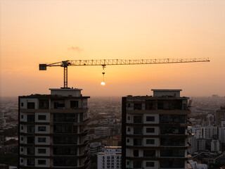 Large construction tower crane positioned over high-rise apartment buildings at sunset © hcarbuccia