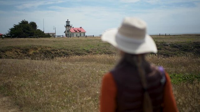 A woman hikes along the trails toward Point Cabrillo Lighthouse in Mendocino California while enjoying the coastal views.