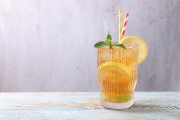 Fototapeta premium Refreshing ice tea with lemon, lime and mint in glass on wooden table, space for text