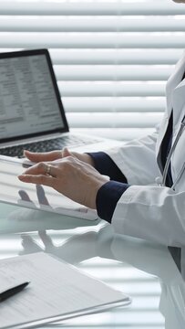 Healthcare professional wearing a lab coat and stethoscope, using a tablet and laptop, collaborating with technology for medical research, digital records, and remote patient care