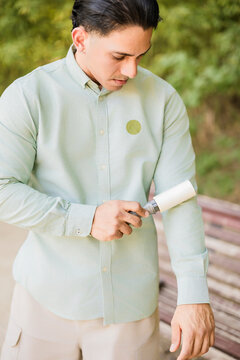 Young man cleaning shirt with a lint roller