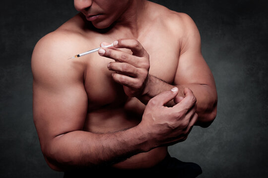 Muscular man injecting performance enhancing drugs into arm