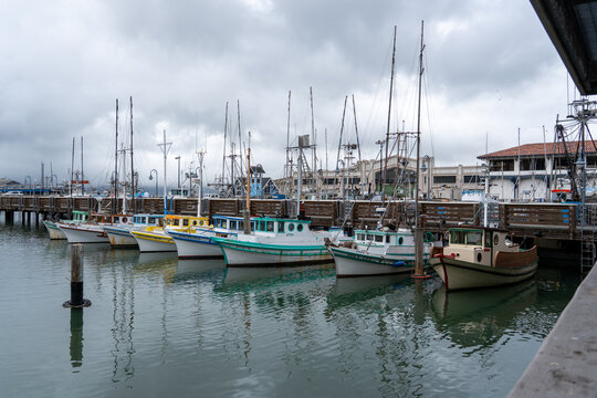 San Francisco, USA - September 09, 2026: Colorful fishing boats moored at Fisherman's Wharf. A classic waterfront scene beneath dramatic clouds reflecting the city's rich maritime heritage.