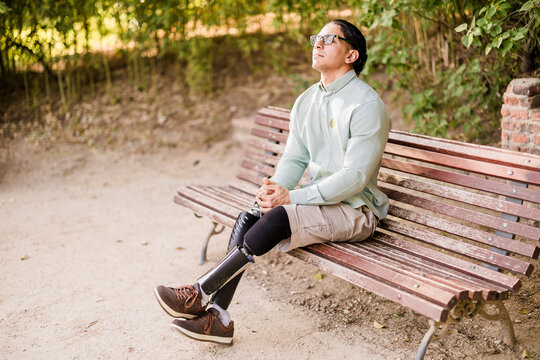 Latino man with prosthetic legs sitting contemplating in park