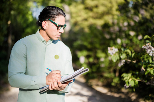 Latino biologist recording plant observations for climate study