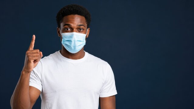 Young Man Wearing Medical Face Mask Pointing Up with Index Finger
